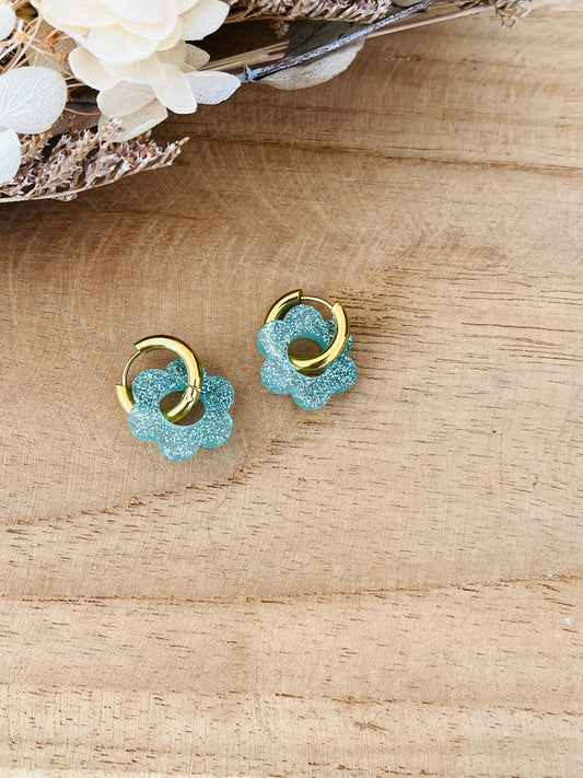 Boucles d'oreilles créoles fantaisie faites main.
Créoles en acier inoxydable doré de 15mm.
Fleur en acrylique de 18mm bleu pailleté.
Bijou fantaisie fait main.