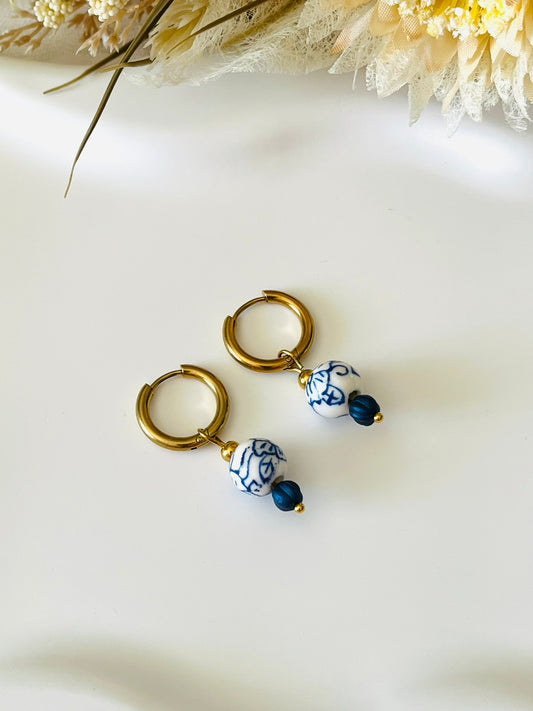 Boucles d'oreilles fantaisie fait main.
Créoles en acier inox doré. Perles rondes en céramique blanche, motif floral bleu.
Bijou fait main