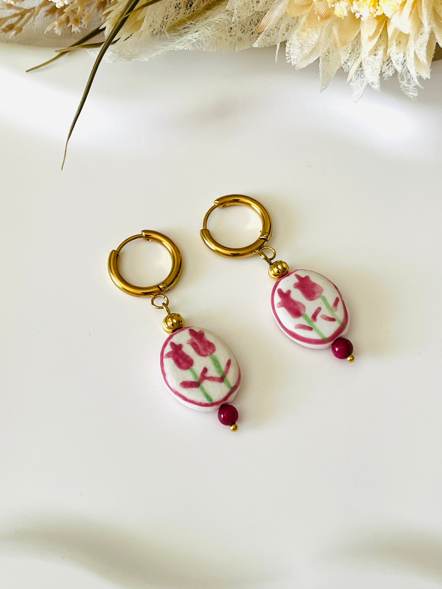 Boucles d'oreilles fantaisie fait main.
Créoles en acier inox doré. Perle ovale en céramique blanche motif tulipe rose.
Bijou fait main.