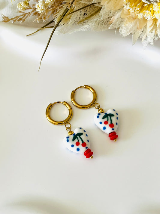 Boucles d'oreilles fantaisie fait main.
Créoles rondes en acier inoxydable doré. Perles coeur en céramique blanc avec motif cerise rouge et pois bleus.
Bijou fait main.