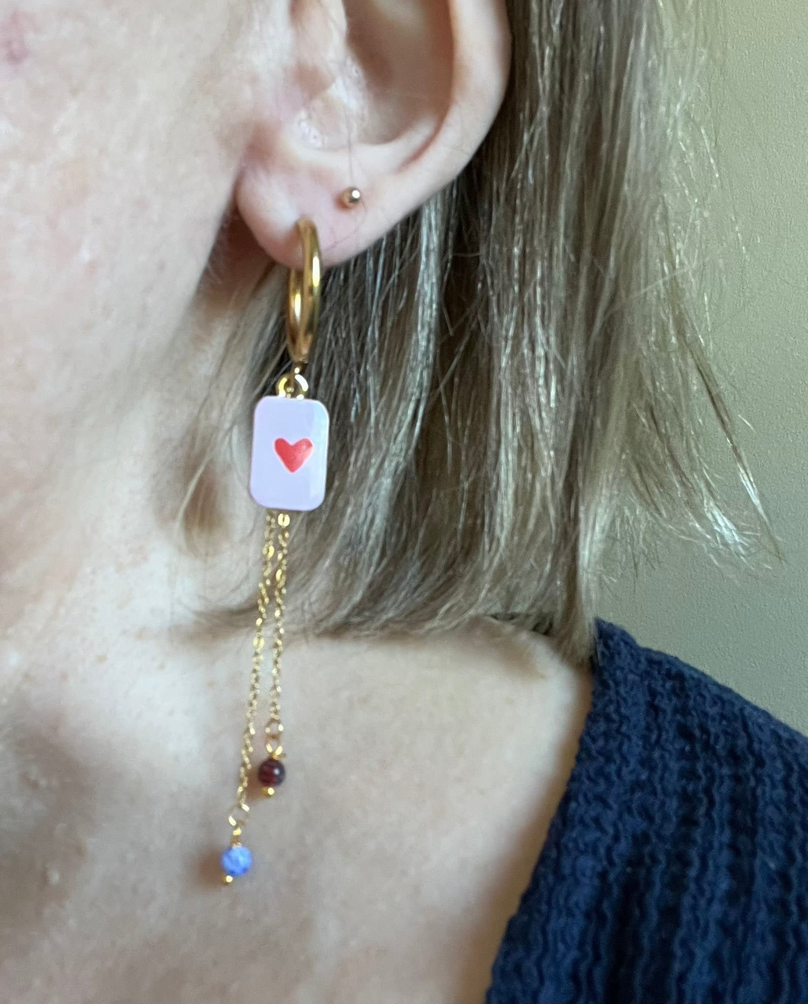 Boucles d'oreilles fantaisie fait main.
Créoles en acier doré.
Pendentif rectangle rose orné d'un coeur rouge.
2 Chainettes de longueur asymétrique réhaussées de perles millefiori dans les tons rouge et bleu.
Bijou fait main
