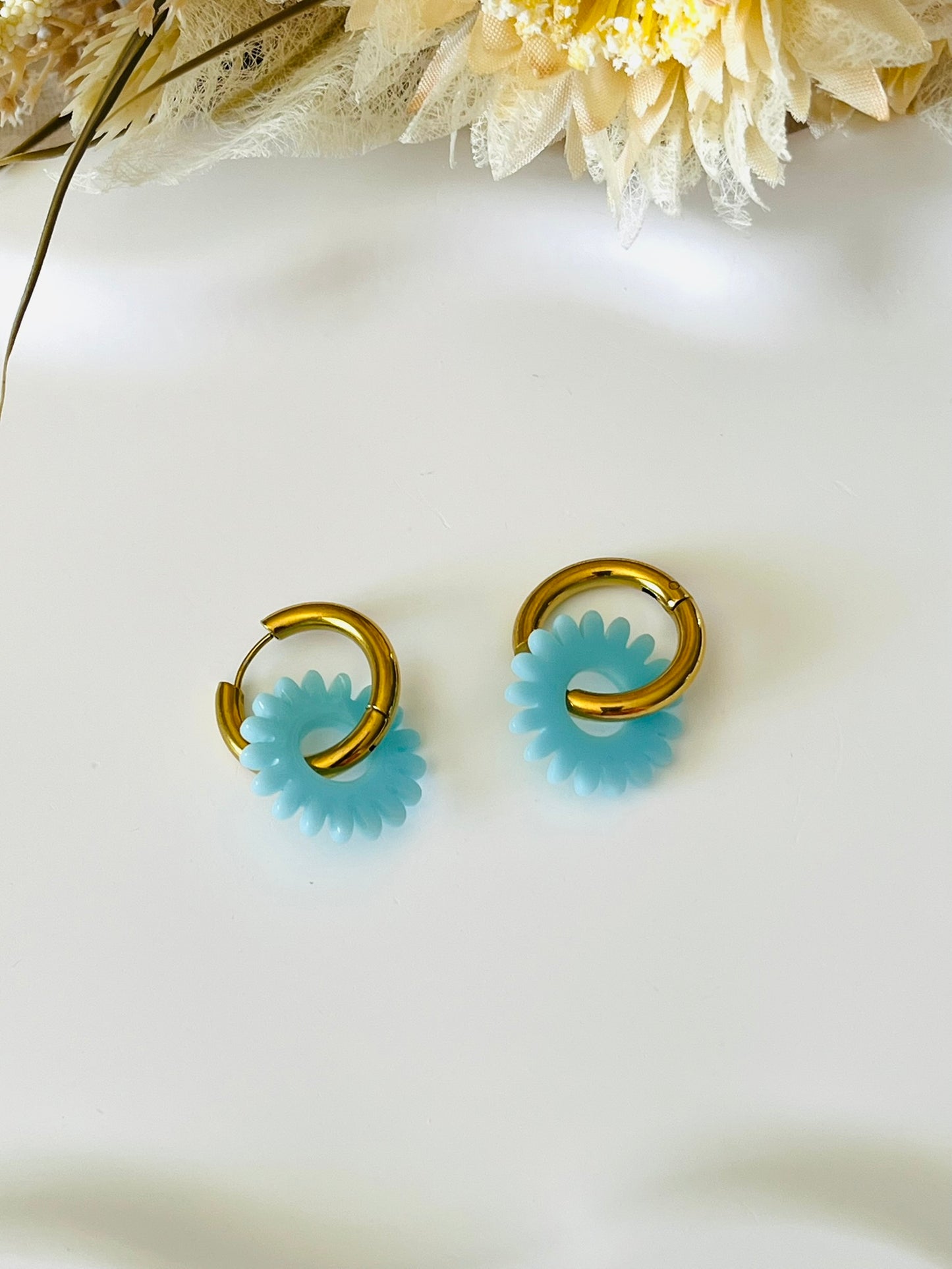 Boucles d'oreilles fantaisie.
Créoles en acier inoxydable doré.
Pampilles fleur, marguerite en acrylique bleu ciel.
Bijou fantaisie fait main.