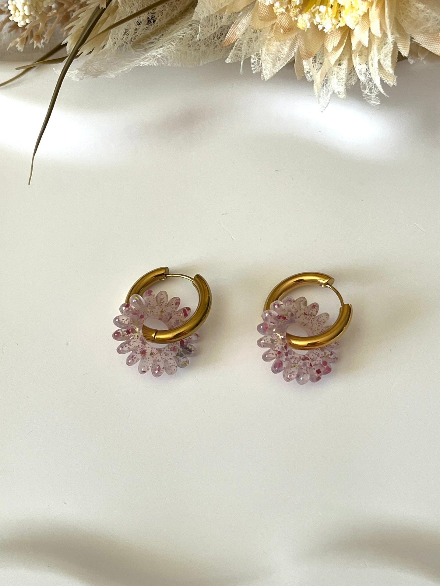 Boucles d'oreilles fantaisie.
Créoles en acier inoxydable doré.
Pampilles fleur, marguerite en acrylique pailleté rose.
Bijou fantaisie fait main.