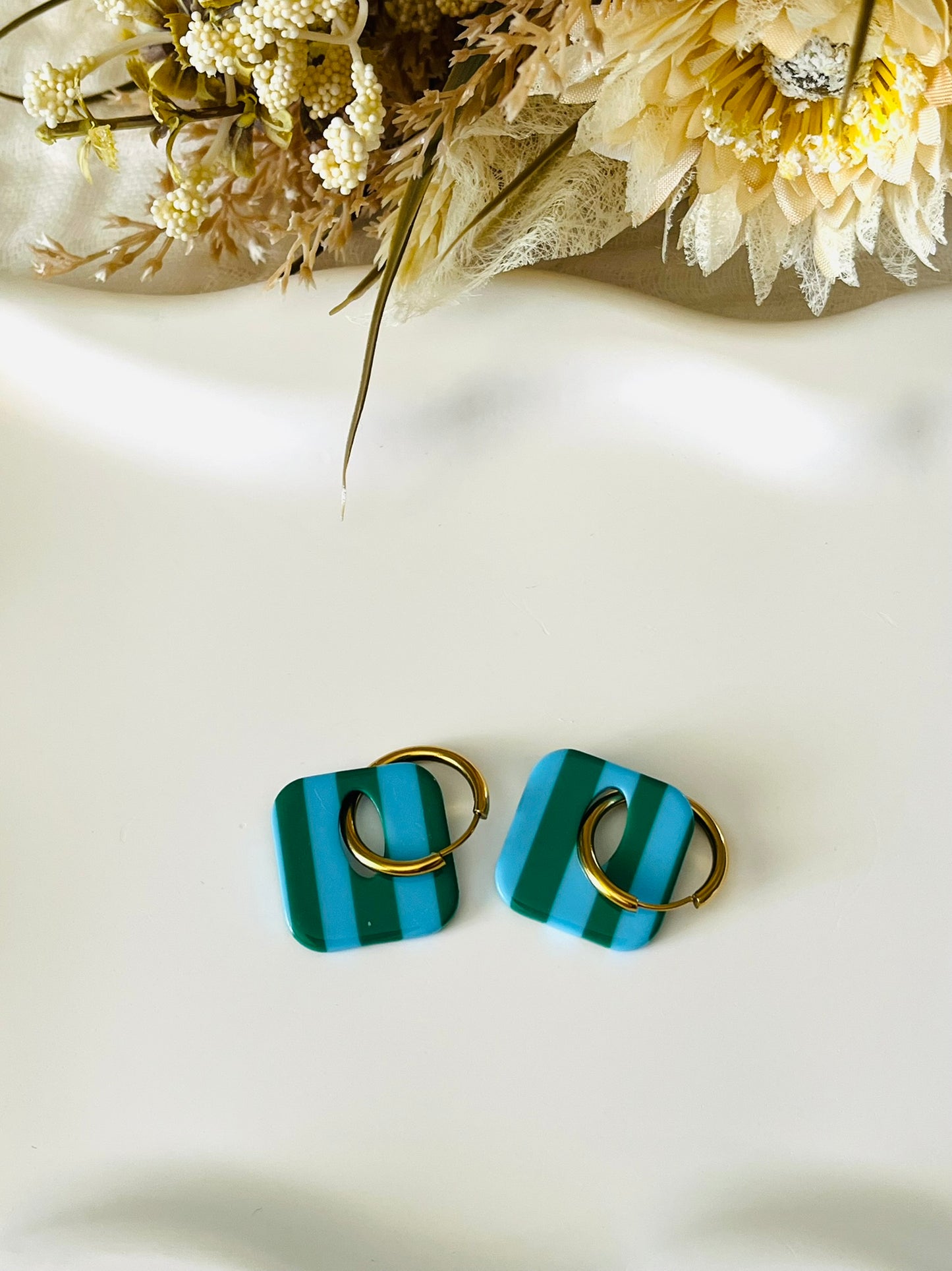 Boucles d'oreilles fantaisie fait main.
Créoles en acier inoxydable avec pampilles interchangeables.
Pampilles carrées bicolores rayées vert et bleu.
Bijou fantaisie fait main.
