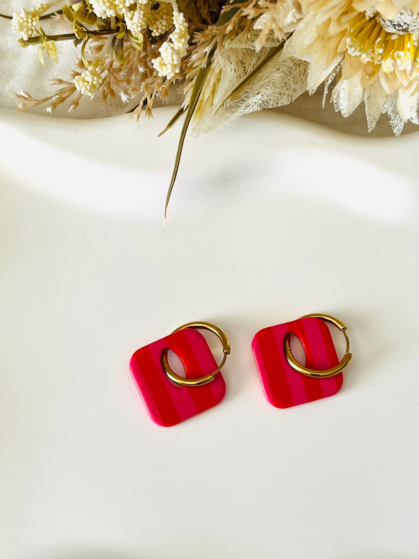 Boucles d'oreilles fantaisie fait main.
Créoles en acier inoxydable avec pampilles interchangeables.
Pampilles carrées bicolores rayées rose et rouge
Bijou fantaisie fait main.