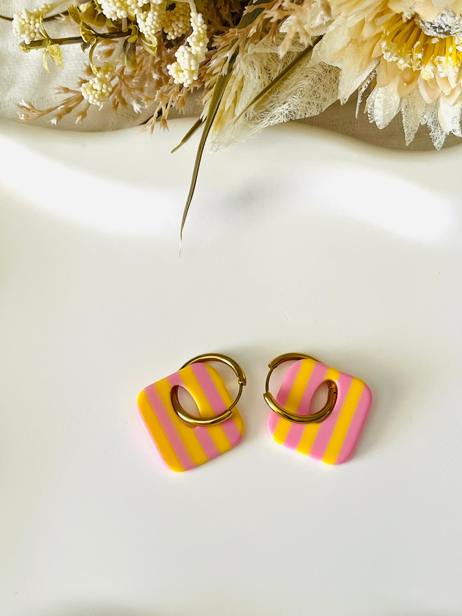 Boucles d'oreilles fantaisie fait main.
Créoles en acier inoxydable avec pampilles interchangeables.
Pampilles carrées bicolores rayées jaune et rose.
Bijou fantaisie fait main.