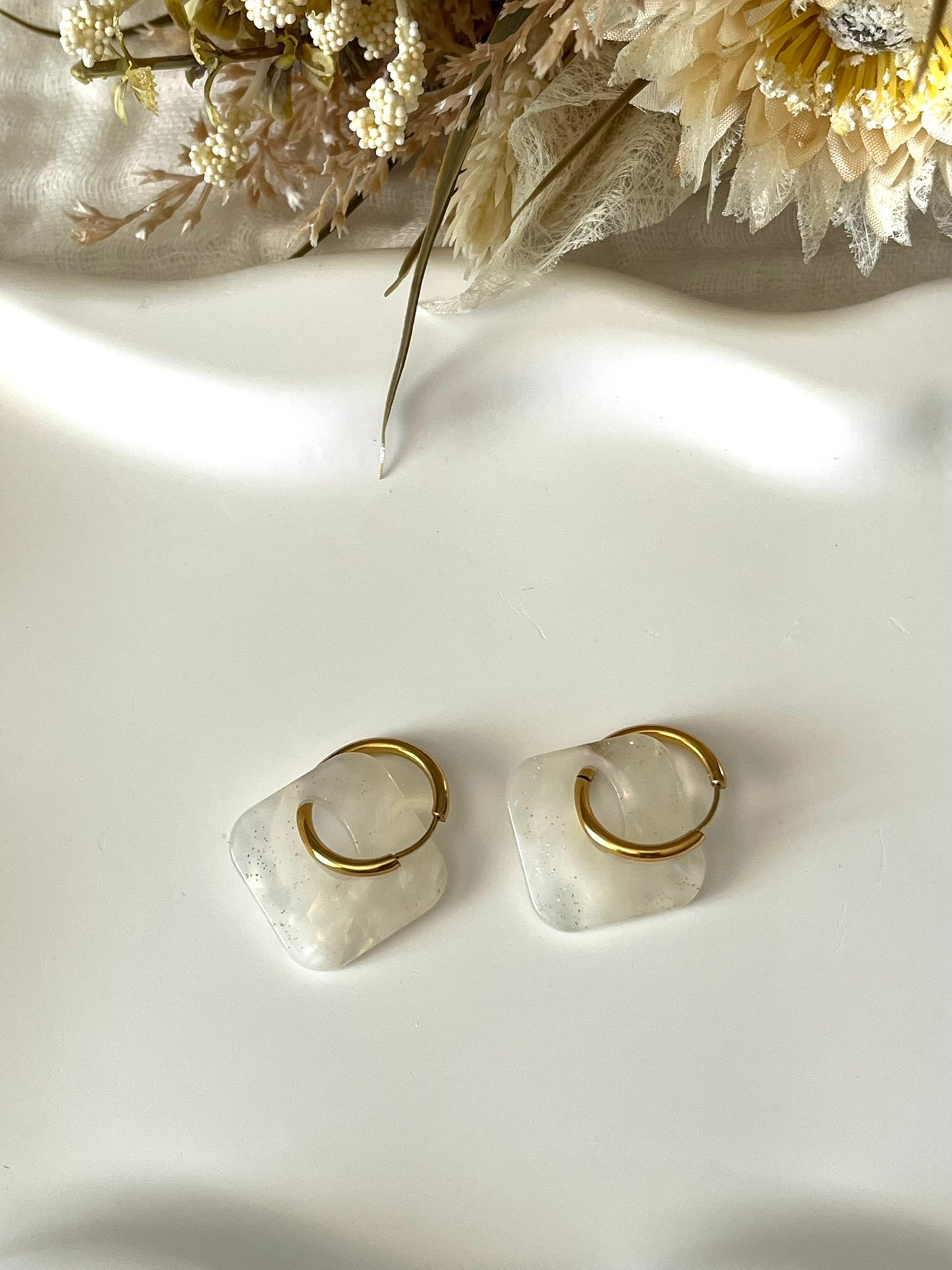 Boucles d'oreilles fantaisie fait main.
Créoles en acier inoxydable avec pampilles interchangeables.
Pampilles carrées couleur marbré blanc nacré pailleté et transparent.
Bijou fantaisie fait main.